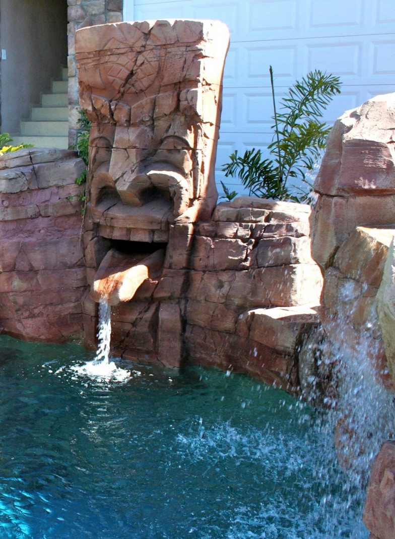 Tribal-themed waterfall flowing into a pool, combining cultural motifs with natural beauty for a serene and elegant outdoor space.