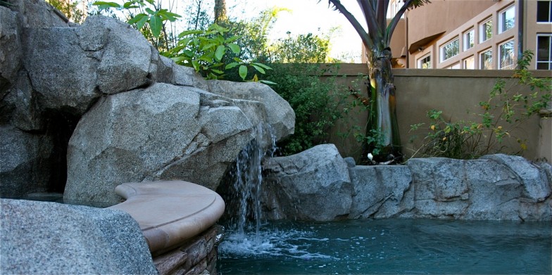 Pool with a stunning waterfall feature, creating a serene and luxurious atmosphere perfect for relaxation and enjoyment.